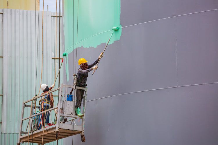 our staff member painting the exterior walls of a tucson business