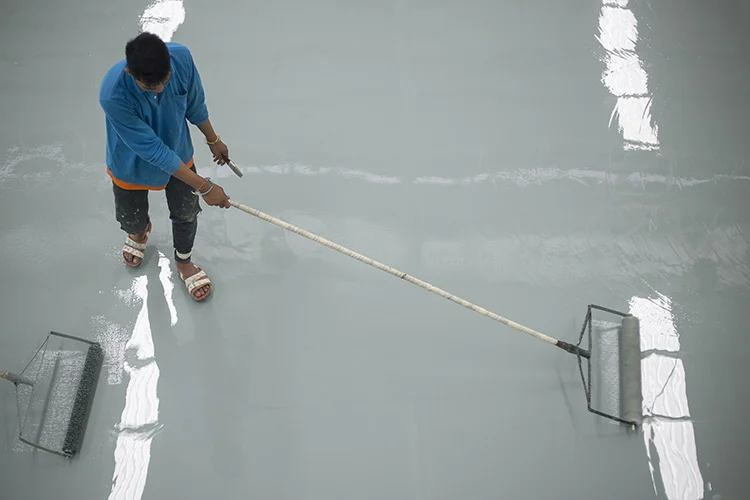 Worker Applying Epoxy Paint on Concrete Floor